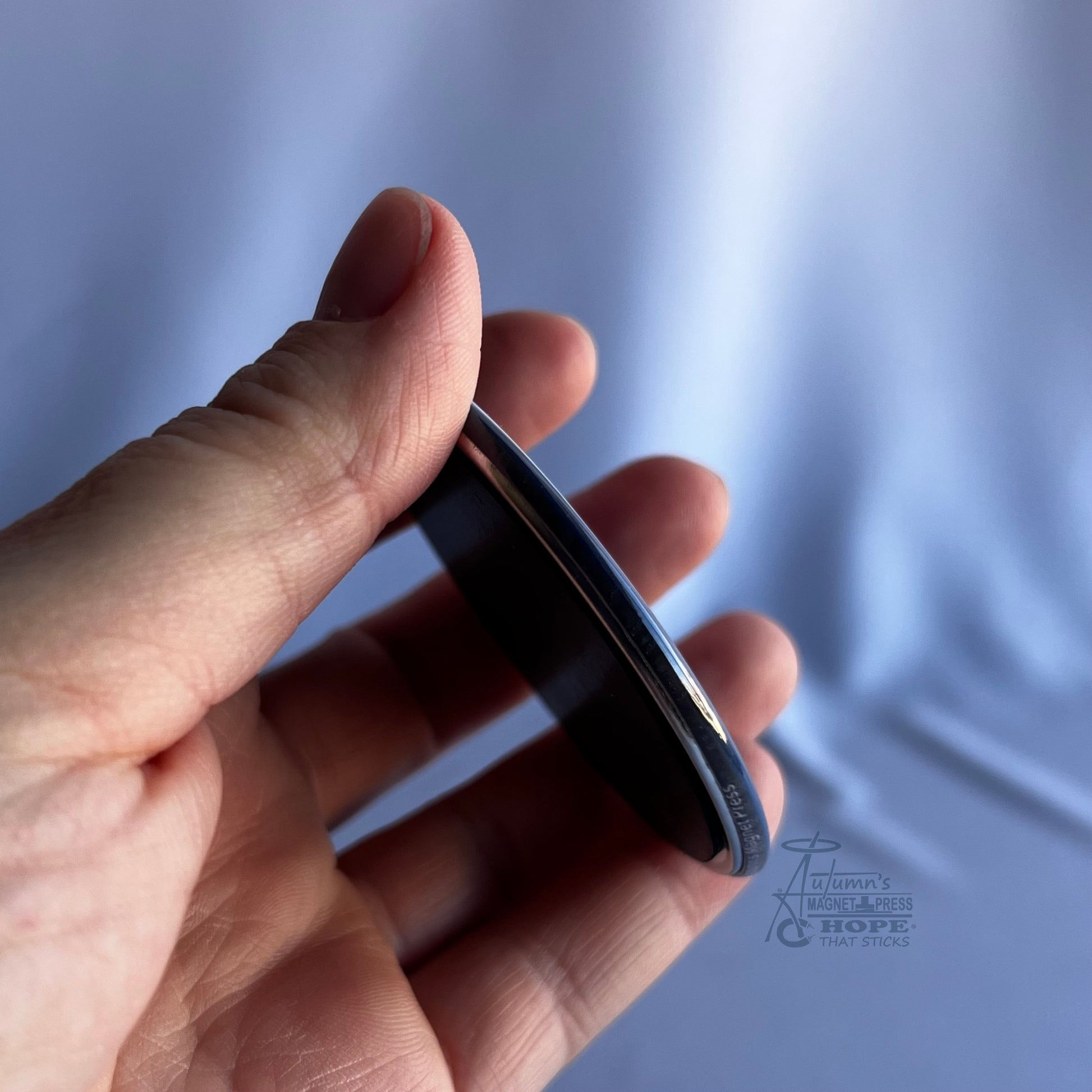 2.5 inch round custom photo magnet side view showing thickness in hand