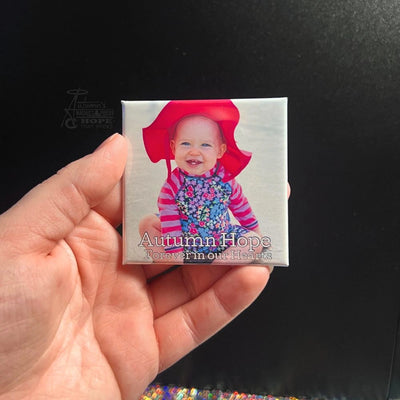 Hand holding a square photo magnet featuring a smiling child in a red hat, symbolizing love, remembrance, and legacy from Autumn’s Magnet Press.