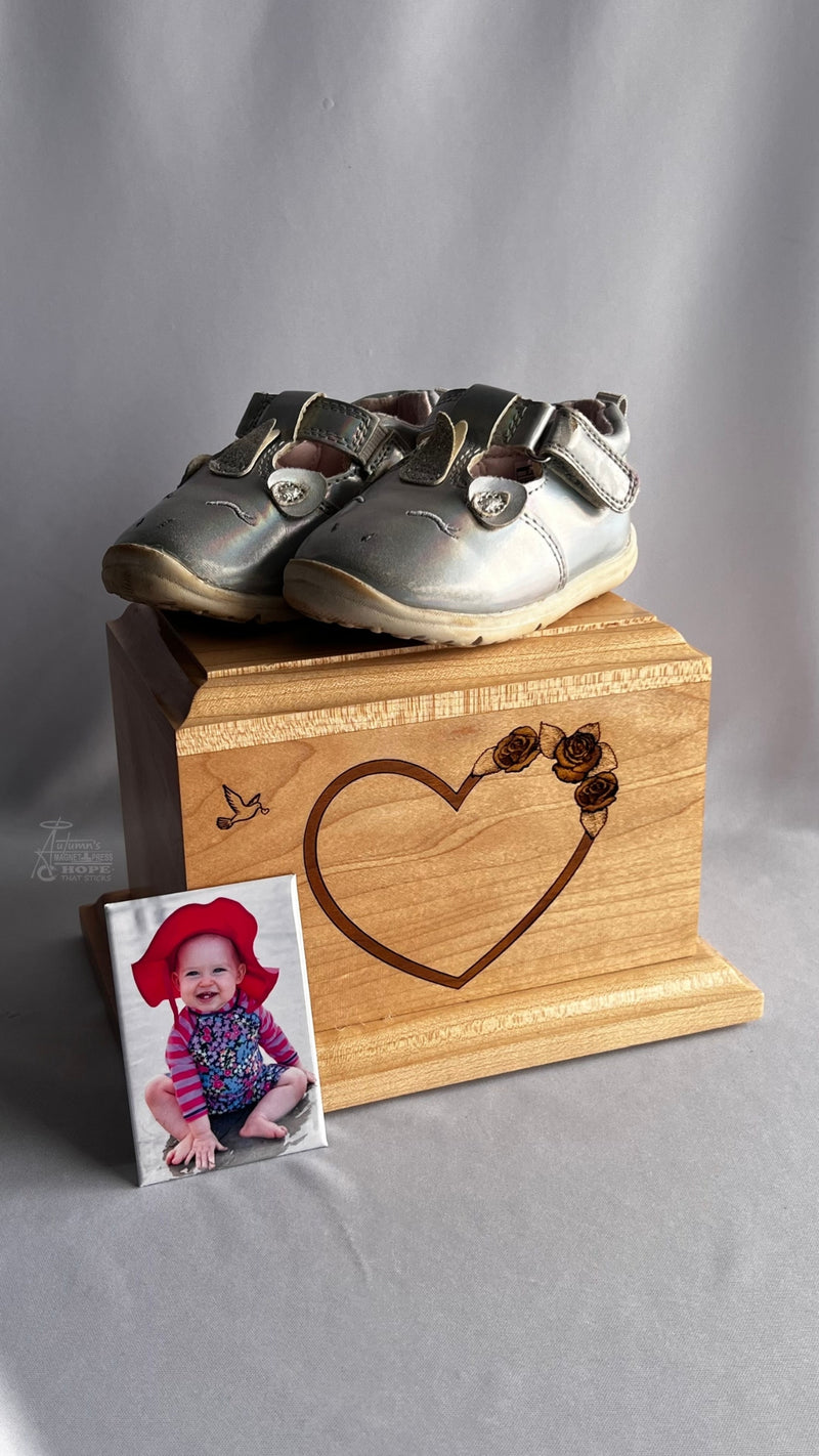 Memorial photo magnet featuring a baby photo displayed beside Autumn Hope’s wooden urn and baby shoes in a remembrance setting.