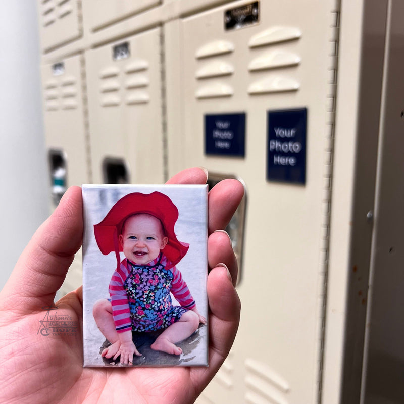 Custom baby photo magnet featuring a smiling baby in a red sun hat held in hand in front of school lockers.