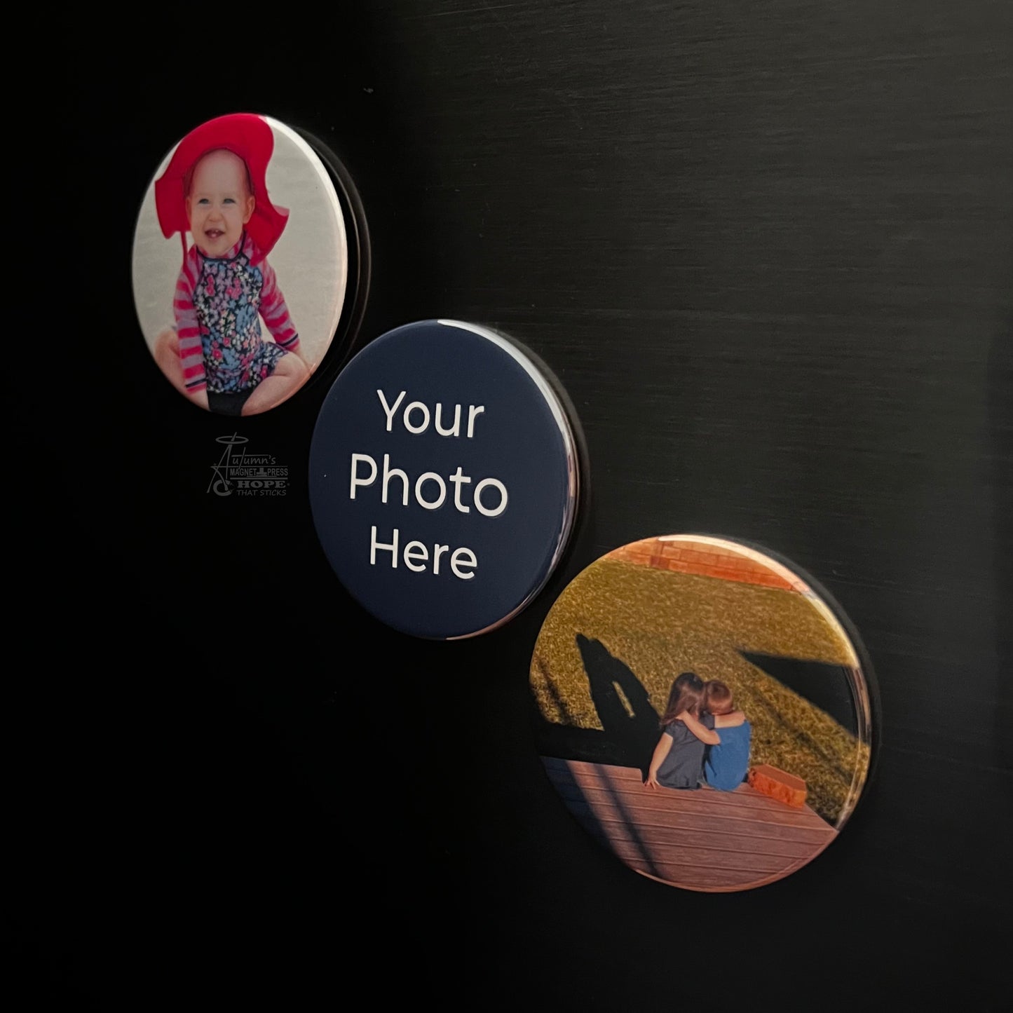 Set of 3 round custom photo magnets with baby and family photos on a dark metal surface