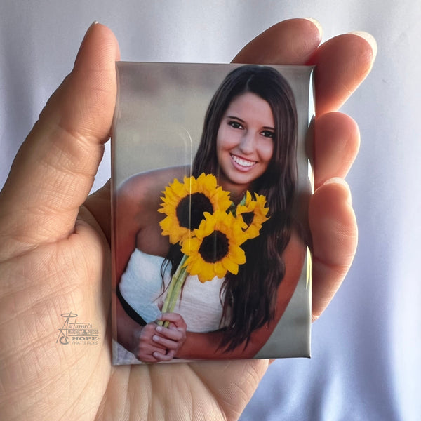 Custom senior portrait photo magnet featuring a smiling young woman holding sunflowers held in hand against a soft white background.