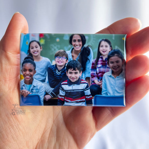 Custom teacher classroom photo magnet featuring a smiling teacher with her students held in hand against a soft white background.